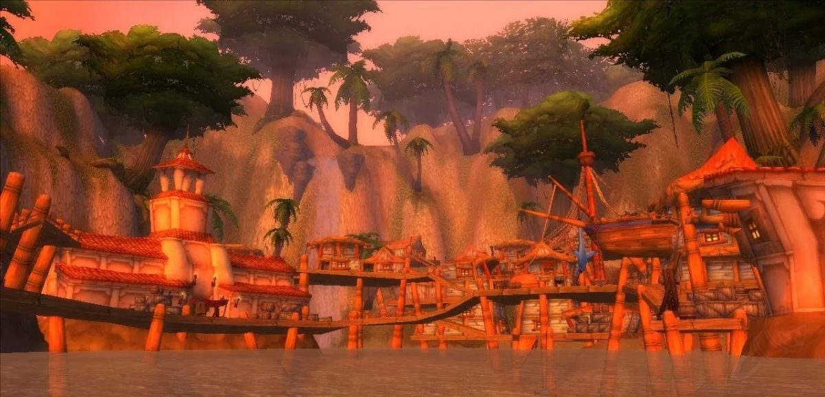 An image of Booty Bay in Stranglethorn Vale at sunset. The docks of WoW's most famous mid-level questing hub have an orange tint to them and are backdropped by lush green trees and granite cliffs.