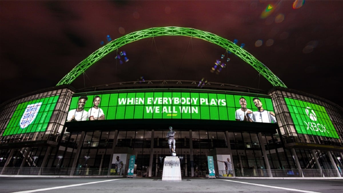 A green Xbox banner screen and arch with the words "when everybody plays, we all win" flashing across the screen.