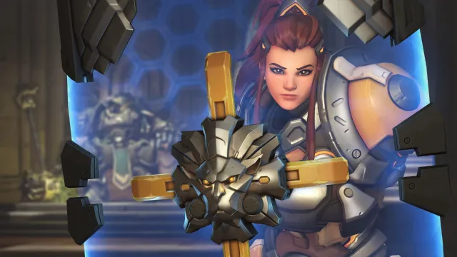 Brigitte holds her shield up as she looks into the camera.