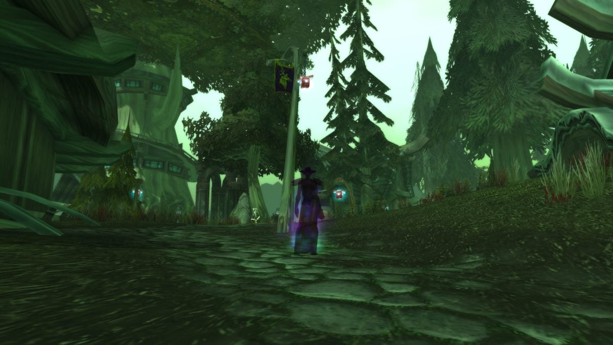 A Shadow Priest stands in Feralas in WoW Classic, they are using their Shadowform and taking on the appearance of a female Night Elf wearing a cloth hat and robe.