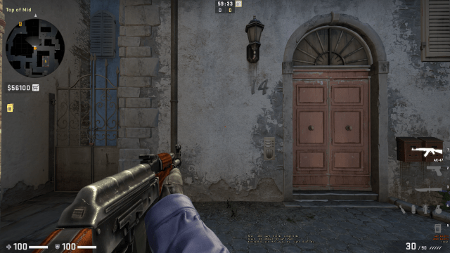 CS:GO player aiming his AK-47 toward a wall on de_inferno