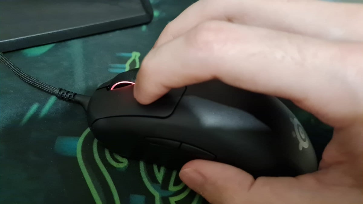 A hand positioned on top of a mouse ready to perform drag clicking.