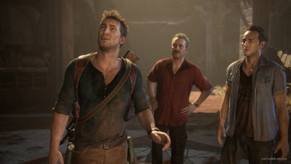 Nathan Drake stands with his companions in a damaged building in Uncharted.
