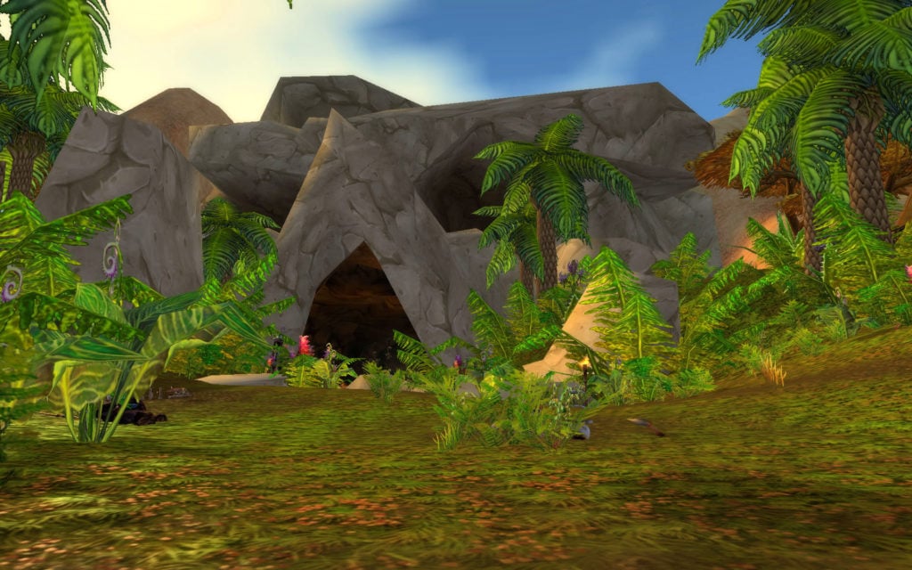 Wailing Caverns entrance in WoW Classic featuring a cave and lush jungle trees.