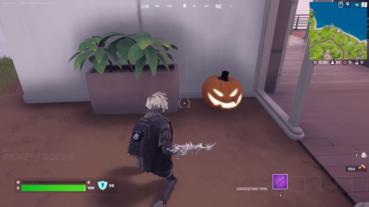 A screengrab from Fortnite showing a character kneeling in front of a Jack-o-Lantern