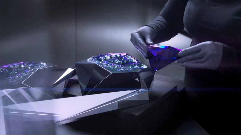A person places a piece of a crystal trophy into place