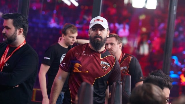 Photo taken of male CS:GO coach kassad during a 2019 tournament. He's wearing a white Supreme cap and Renegades' red and black jersey.