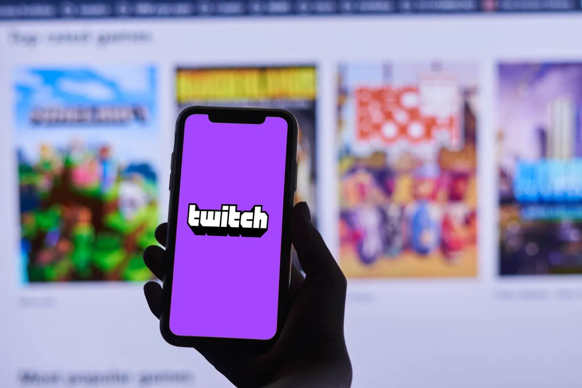 Twitch logo on a purple background on a phone, with more Twitch categories showing in the background.