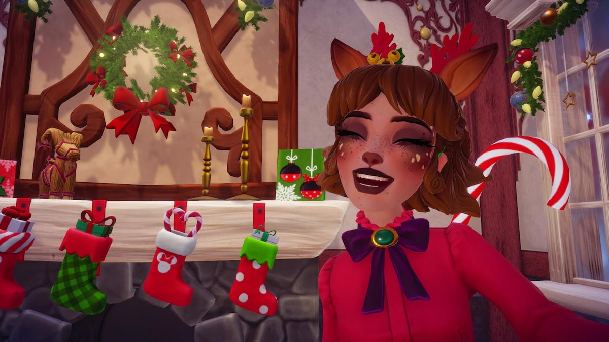 A player with reindeer antlers and ears smiling with her eyes closed and a christmas fireplace behind her in disney dreamlight valley.