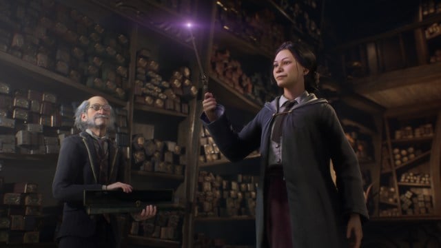 A young witch holds a wand while wandmaker Ollivander stands nearby in Hogwarts Legacy.