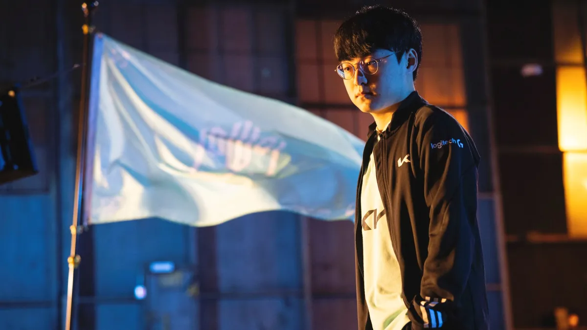 ShowMaker of DWG KIA stands in front of a flag with his team's logo on it.