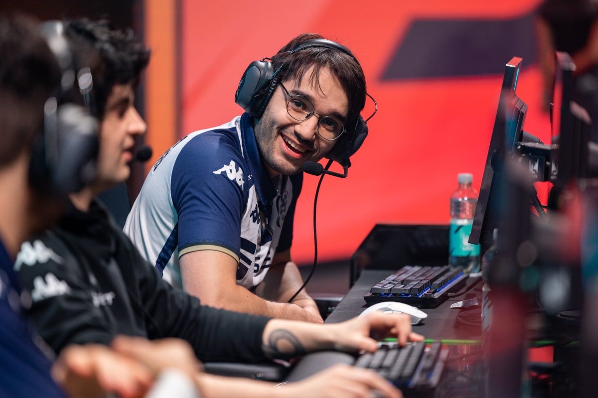 Hylissang competing on stage, wearing a headset and seemingly laughing with his teammates.