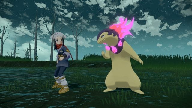 The player character in Legends: Arceus stands next to a Typhlosion in a wooded area at night.