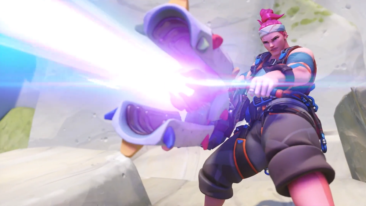 Zarya fires a purple beam from her weapon, wearing a sweat band to keep up her pink hair.