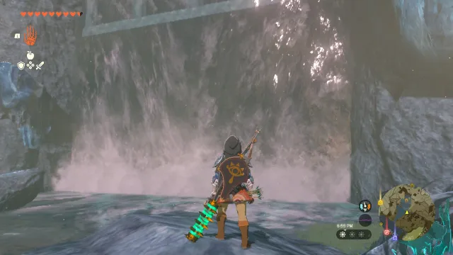 Link stands in front of a waterfall, which appears to have a hidden entrance behind it.