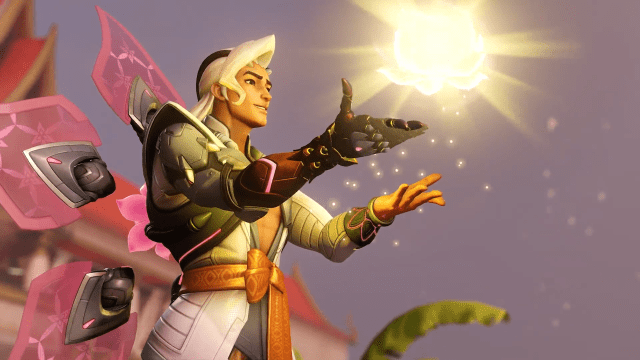 Lifeweaver from Overwatch 2 extends his hands and a bright orb of yellow light emerges from them.