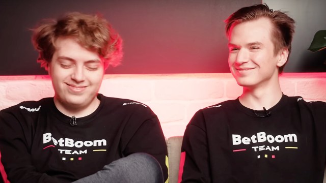 Pure, a Dota 2 player, is pictured sitting next to his teammate smiling.