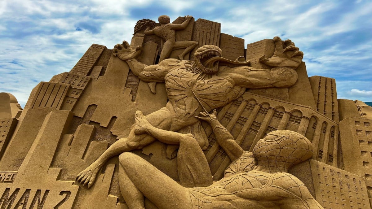 A sand sculpture depicts Venom battling against Spider-Man and Miles Morales.