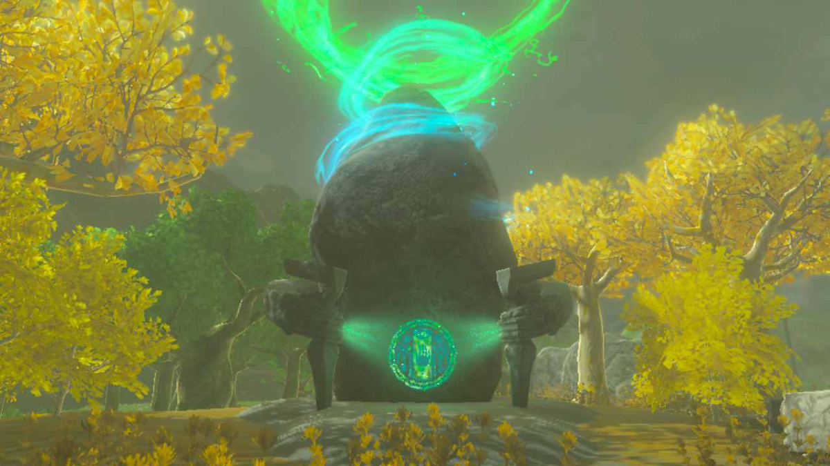 A shrine from Tears of the Kingdom, with a glowing blue and green circle in front and an aura coming from the top. The shrine is surrounded by trees with yellowish leaves.