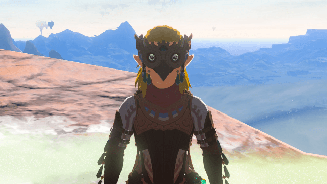 Link stands facing the camera with an owl-like mask. His outfit is brown with green accents.