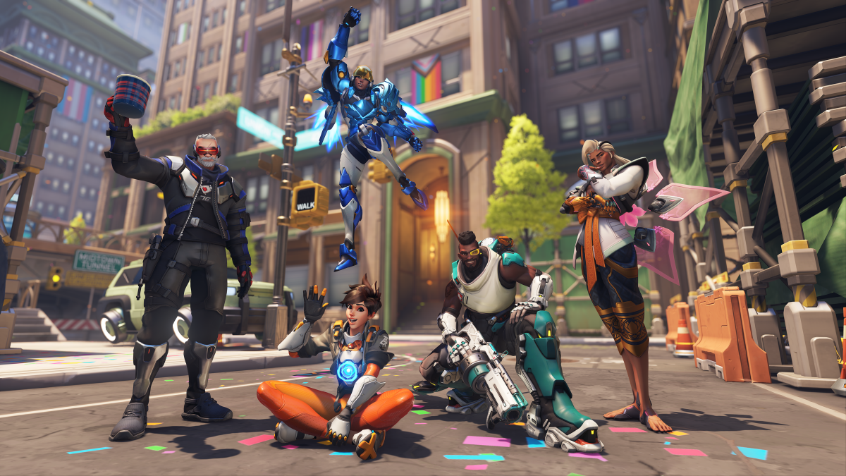 Overwatch's LGBTQ+ heroes standing together with a Midtown Pride parade as the backdrop. Soldier: 76, Tracer, Pharah, Baptiste, and Lifeweaver are all depicted giving different victory poses.