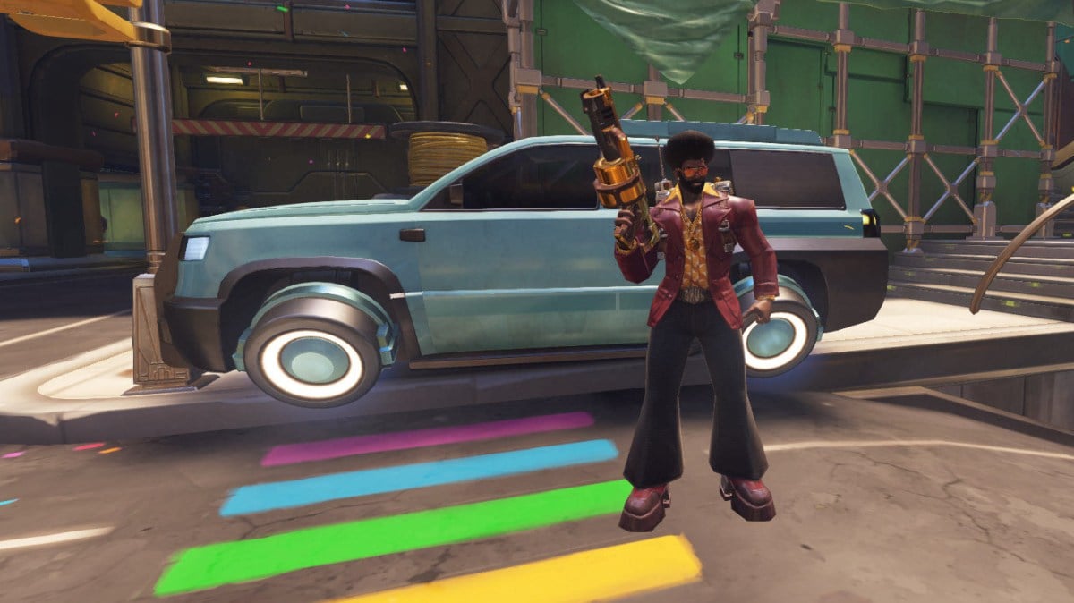 Bisexual baptiste raising his gun and posing in front of what used to be a cop car in overwatch 2's midtown map during the pride event