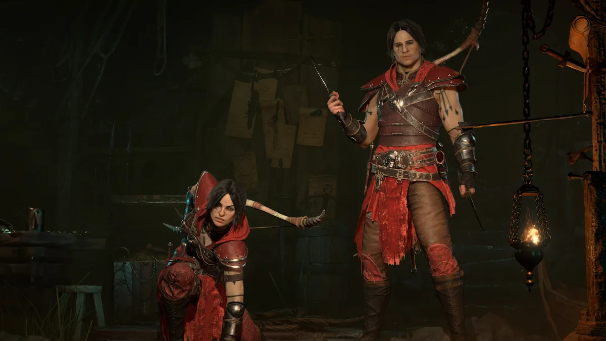 Two Rogues in full gear in Diablo 4, wearing red outfits. The rogue on the left is crouched and prepared to strike.