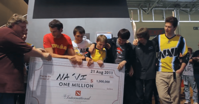 The NAVI team stand with Gabe Newell, Valve CEO, holding a giant cheque after winning The International 2011.