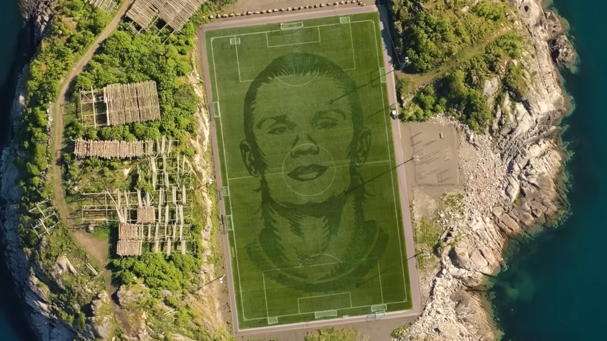 Erling Haaland's face cut into the grass of a soccer pitch.