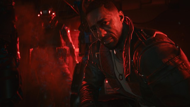 A character played by Idris Elba sitting in a red-lighted room.