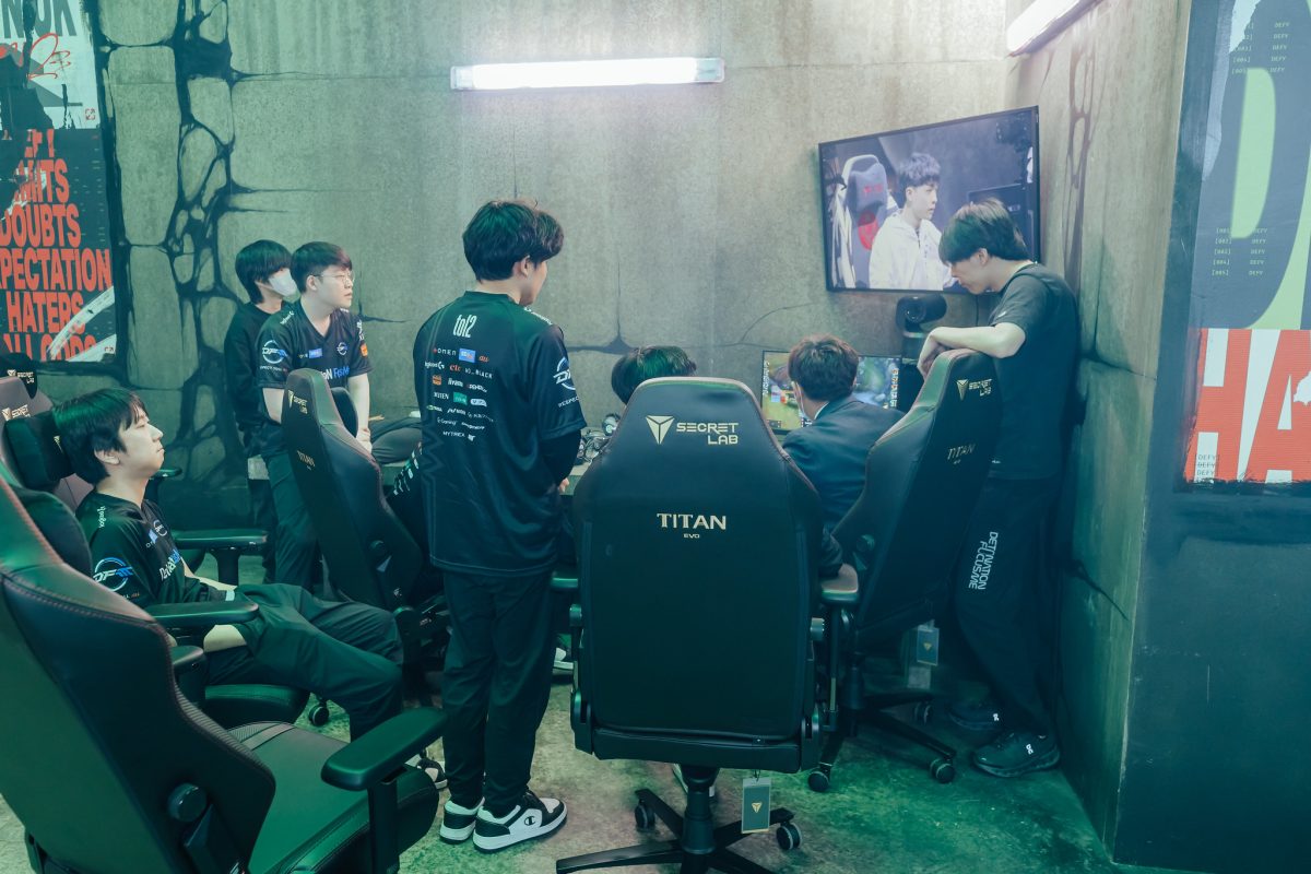 DFM stand around a monitor and review a game at MSI 2023.