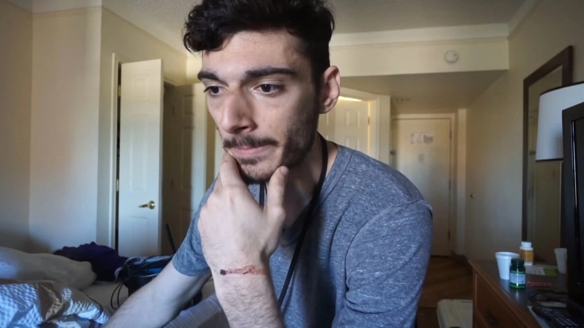 Streamer Ice Poseidon, real name Paul Denino, sits in front of the camera in a hotel room