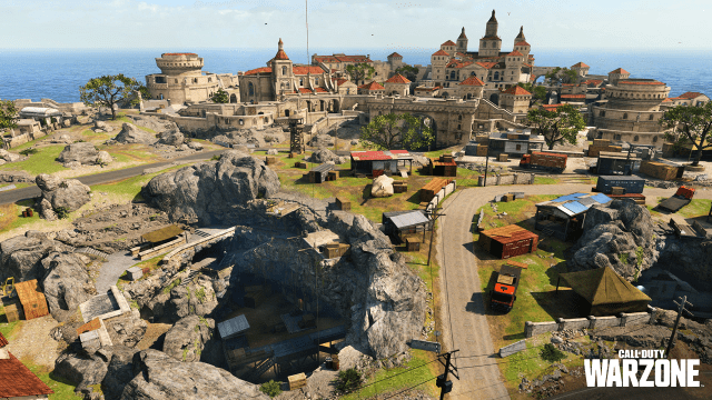A grand castle and town sits in the distance, while an underground cove opens up with a smattering of buildings spread outside the town walls in Warzone.