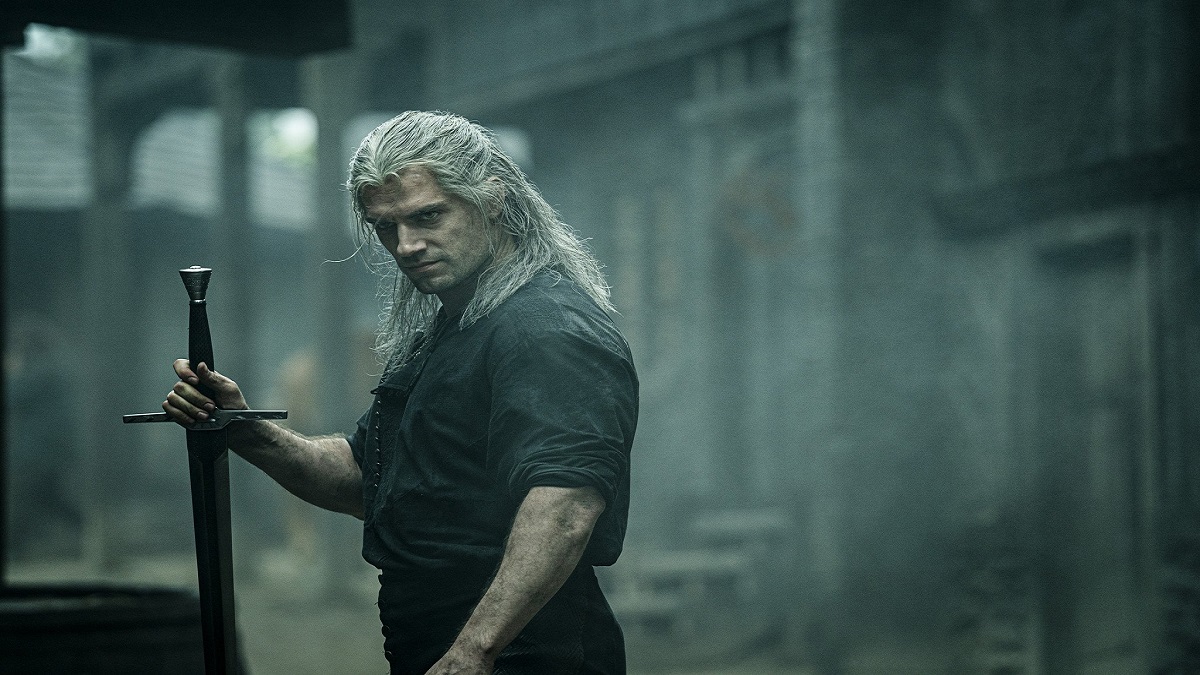 An image of Henry Cavill as Geralt of Rivia brandishing a sword in The Witcher Netflix show.