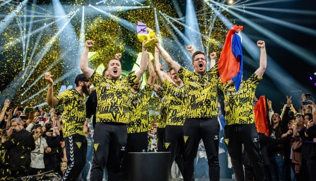 ZywOo and apEX from Vitality lifting the BLAST Paris Major trophy, apEX holding the French flag in his left hand.