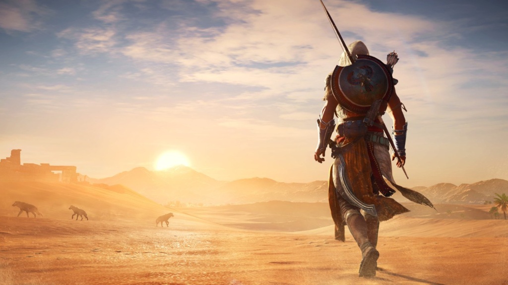 Bayek walks into the sands of a desert while the sun is setting. 