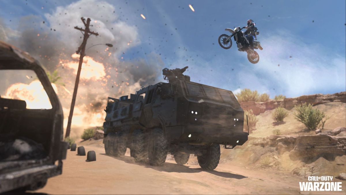 Image showcases an MRAP from Warzone DMZ making its way along a sandy road after an explosion. A dirtbike can be visibly seen in the air jumping over the MRAP.