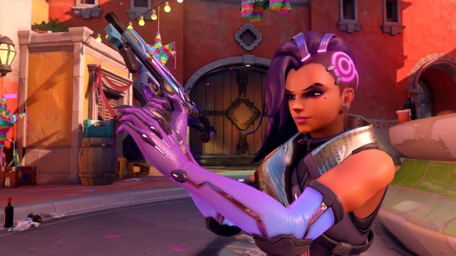 Sombra, from Overwatch 2, standing with her machine pistol ready to fire in a small town square.