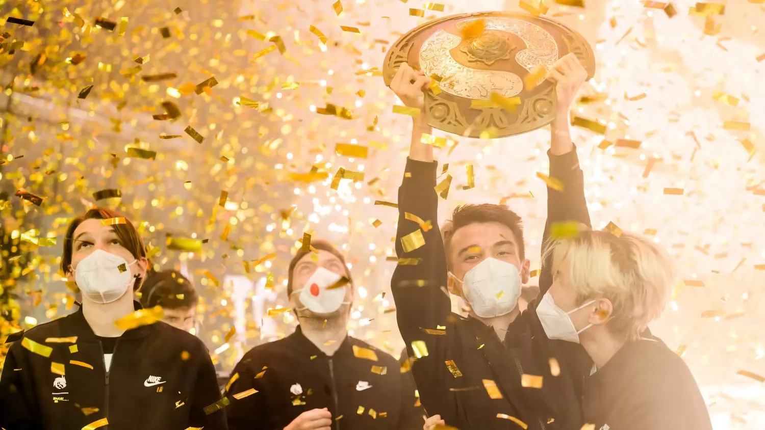 Team Spirit holding the T1 trophy as confetti rains down on them.