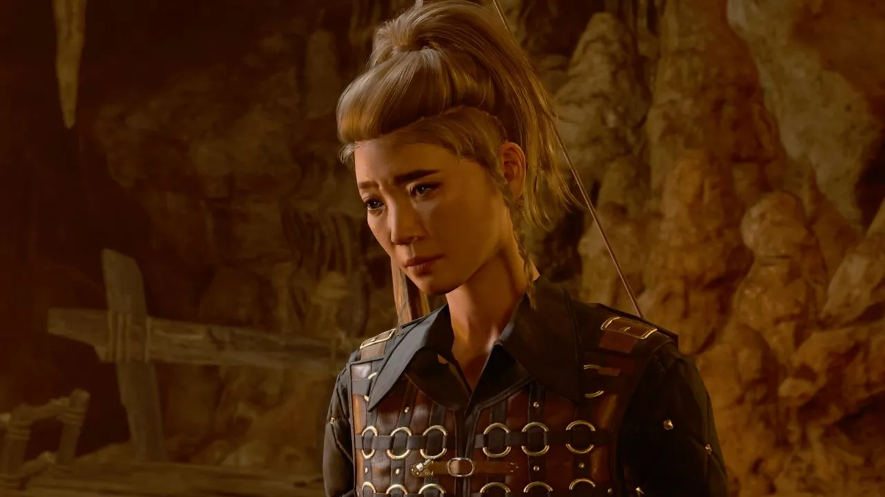 Woman wearing light armor with her hair tied up in a cave in BG3