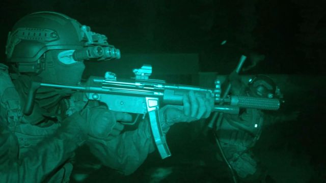 Image showcasing Call of Duty: Modern Warfare (2019) with a night vision filter overlayed. There is a soldier wielding a weapon with a glint of light shining onto it.