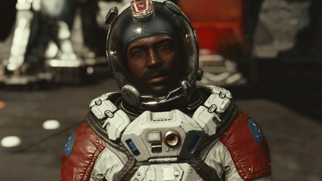 Barrett in Starfield looking at the camera in a space suit with equipment behind him.