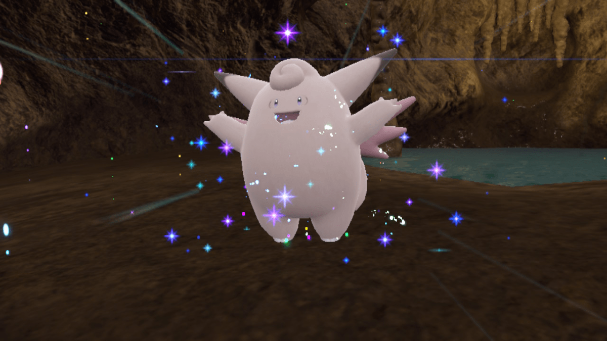 Clefable, a pink marshmallow-like Pokémon with fairy wings, stretches its arms upwards in a cave while surrounded by sparkles.