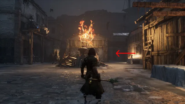 An arrow pointing to an alley to the right of a burning effigy in the Malum District in Lies of P