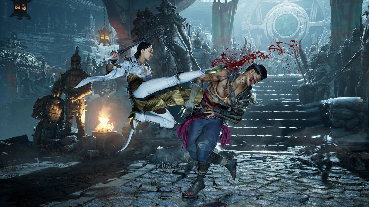 Two characters are fighting each other in a cavern. There is a giant amulet structure behind them, and torches that are lit.