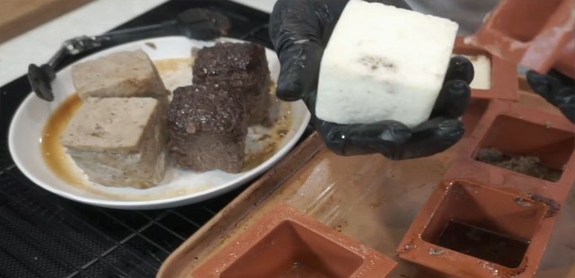 Chunks being prepared, the focus is on the poacked egg but there is also a plate of cube shaped beef and chicken in the background. Screenshot by Dot Esports.