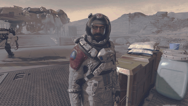 Barrett standing on the moon in the first mission in Starfield next to some chests in a space suit