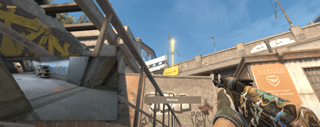 A CS2 character holding an AK-47 and pointing towards a bridge on Overpass.
