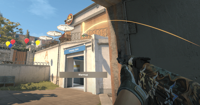 A CS2 character getting ready to throw a flash in Overpass' divider. They're holding an AK-47