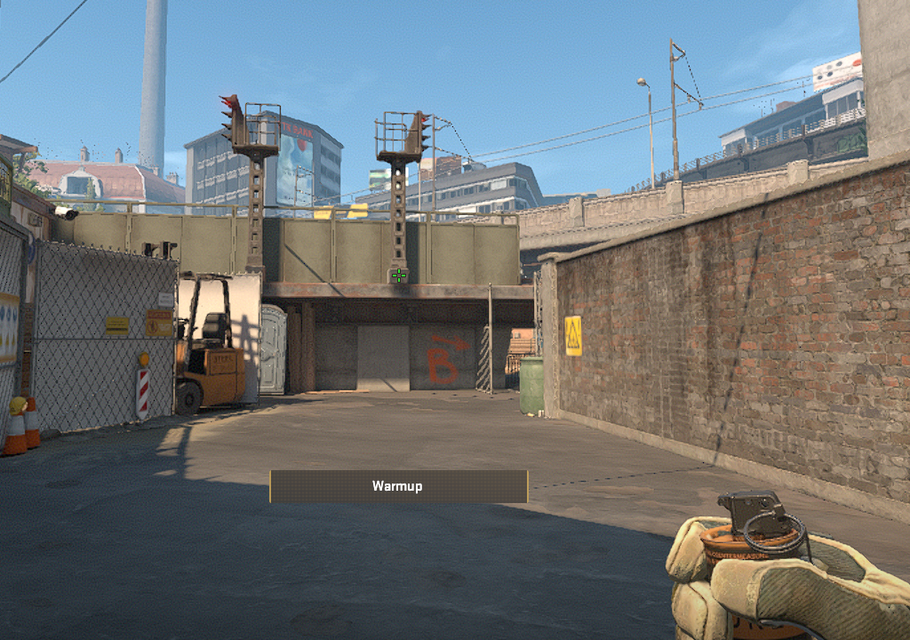 A CS2 character holding a smoke towards Midsite on Overpass.